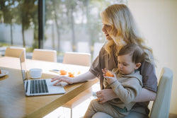 mom working on laptop with baby on lap